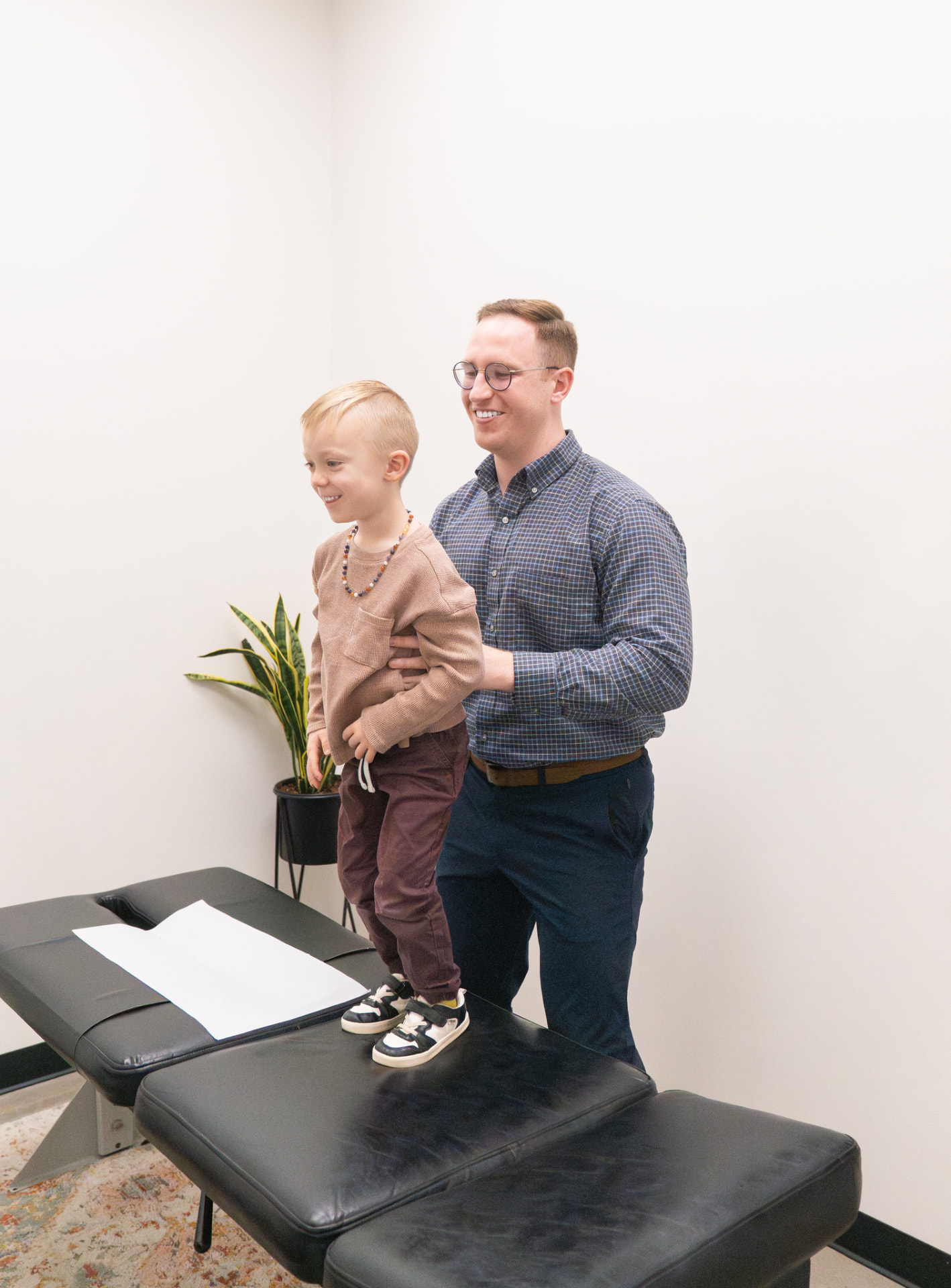 Dr. Landon Blake steadying a young boy standing on the adjusting table at Trail Chiropractic