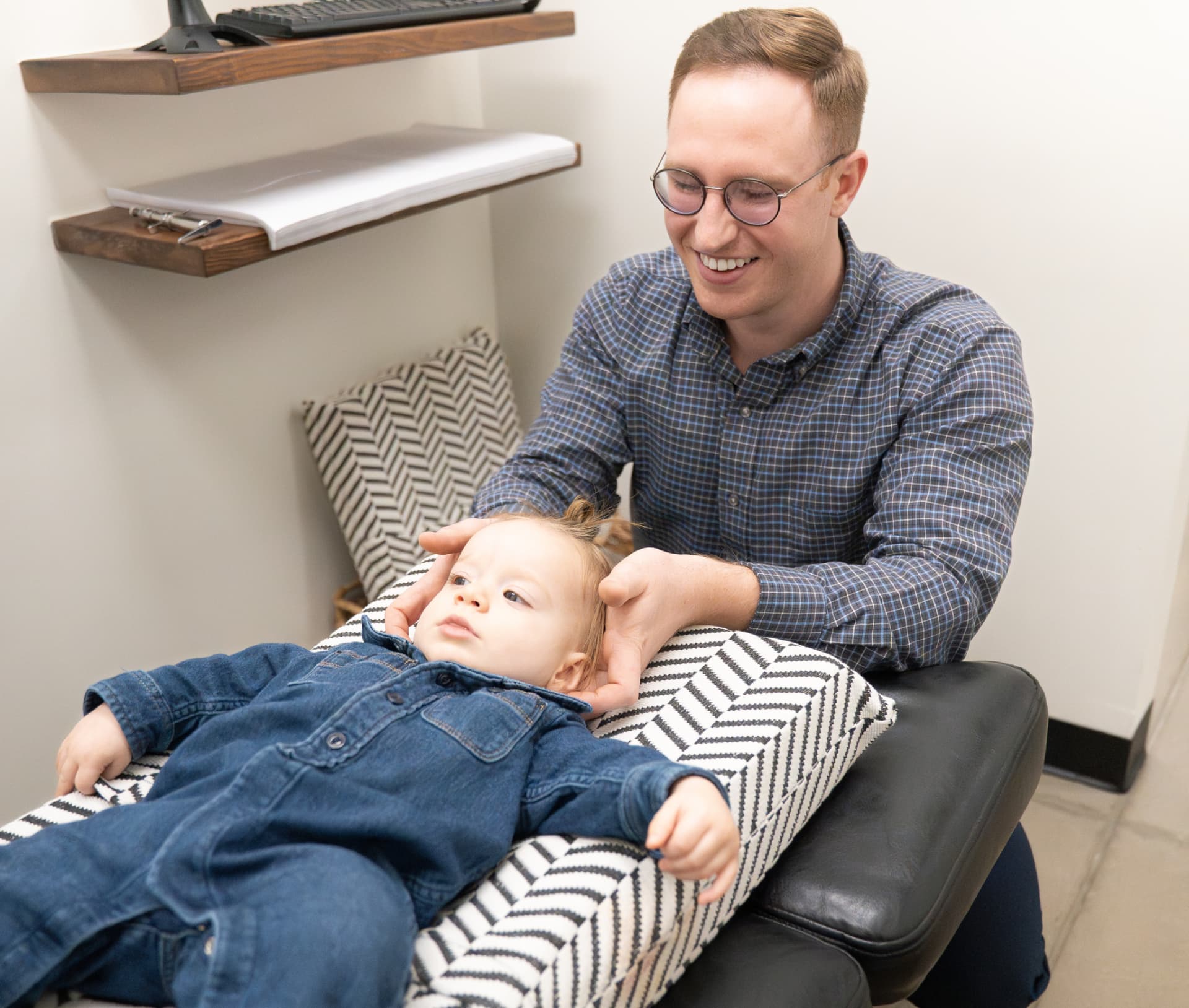 Dr. Landon Blake performing a gentle adjustment on a smiling infant at Trail Chiropractic